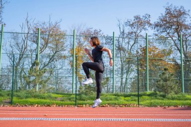 Yaz günü stadyumda genç bayan koşucu eğitimi. 