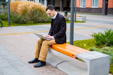 İş adamı dışarıda bilgisayar ve cep telefonuyla çalışıyor.