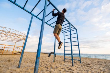 Young fit male training do exercises outdoor on the beach