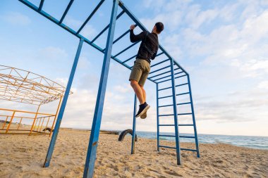 Young fit male training do exercises outdoor on the beach