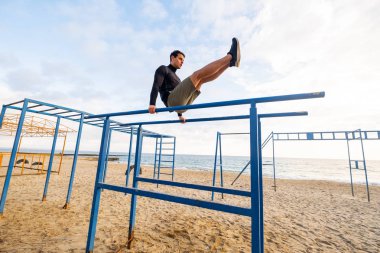 Young fit male training do exercises outdoor on the beach