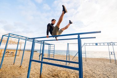 Young fit male training do exercises outdoor on the beach