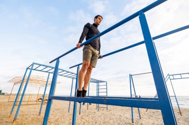 Young fit male training do exercises outdoor on the beach