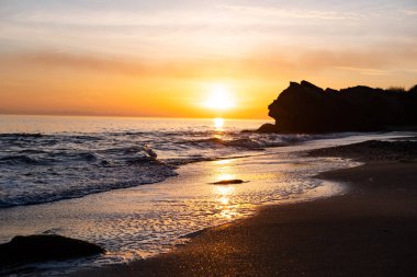 Günbatımı, uçurumlar ve denizle güzel bir manzara.