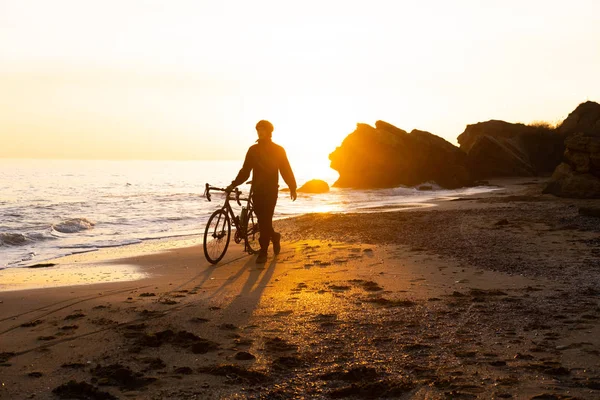 Gün Batımında Kumsalda Kasklı Bisiklet Süren Genç Bir Erkeğin Silueti — Stok fotoğraf