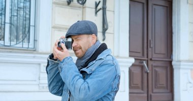 Elinde film kamerası olan genç ve yakışıklı bir gezgin sokak fotoğrafları çekiyor.