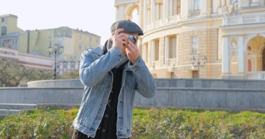 Elinde film kamerası olan genç ve yakışıklı bir gezgin sokak fotoğrafları çekiyor.