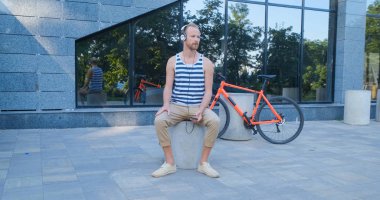 Renkli bisiklet ve kulaklıklı genç yakışıklı erkek müzik dinler ve yaz caddelerinde ata biner.