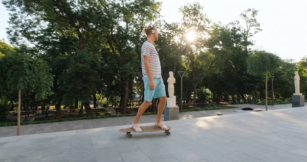 Knappe Jonge Man Met Skateboard Buiten Stad Luisteren Naar Muziek — Stockfoto