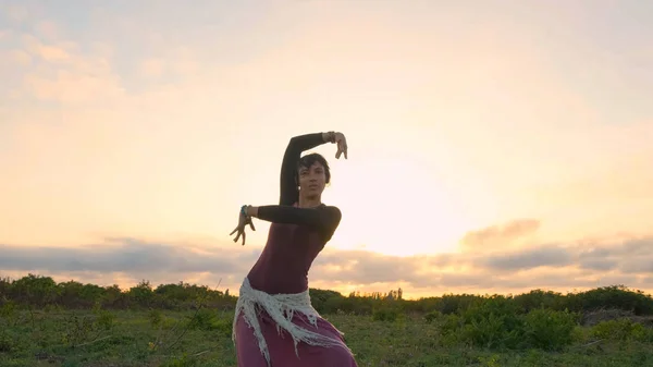 Happy female dance in the summer fields during beautiful sunset