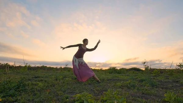 Happy female dance in the summer fields during beautiful sunset