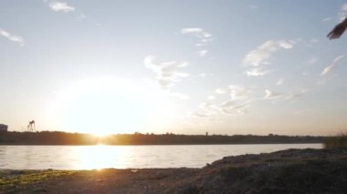 young happy woman in poncho dancing on the beach, beautiful sunset background