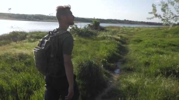 夏の晴れた日に川の近くを旅行するバックパッカーのカップル — ストック動画
