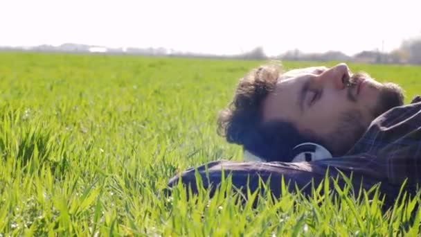 Young Male Relaxing Green Grass Listen Music Big White Headphones — Stock Video