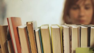 Genç kadın raf üzerinde kitap seçin
