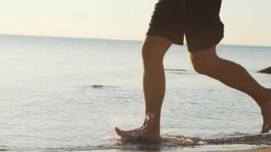 Sabahları güneşli plajda genç erkek koşucu eğitimi.