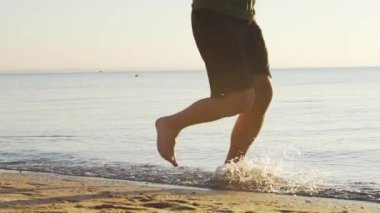 Sabahları güneşli plajda genç erkek koşucu eğitimi.