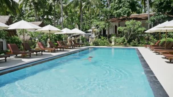 Mädchen schwimmt im Pool eines schönen Resorts — Stockvideo