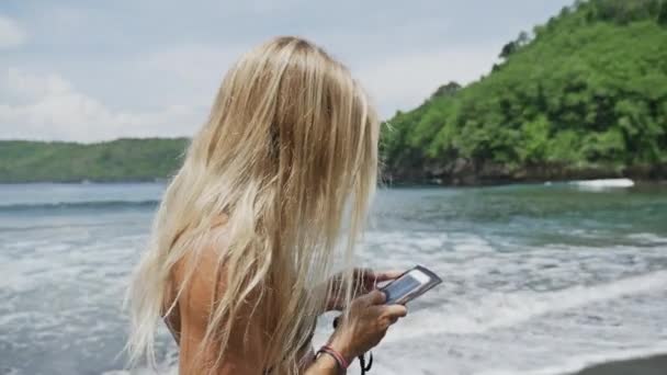 Dziewczyna spaceru z smartphone na plaży — Wideo stockowe