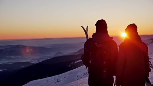 Esquiador y snowboarder admirando una hermosa puesta de sol — Vídeo de stock