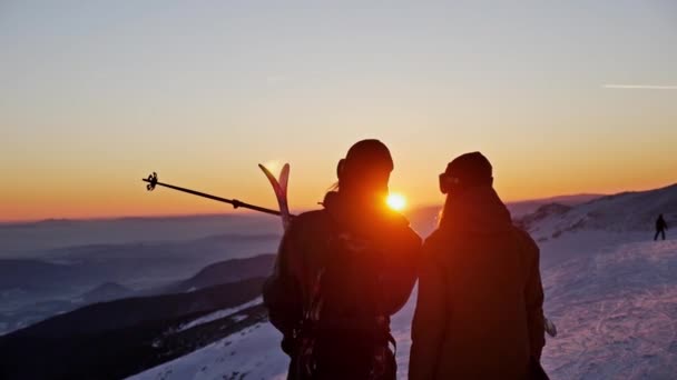 Лижник і сноубордист захоплюються красивим заходом сонця — стокове відео