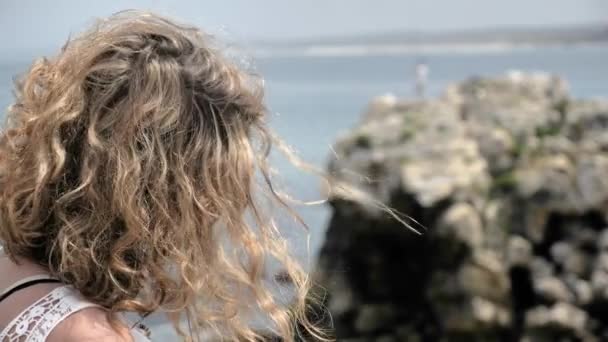 Девушка на скалистом берегу моря — стоковое видео