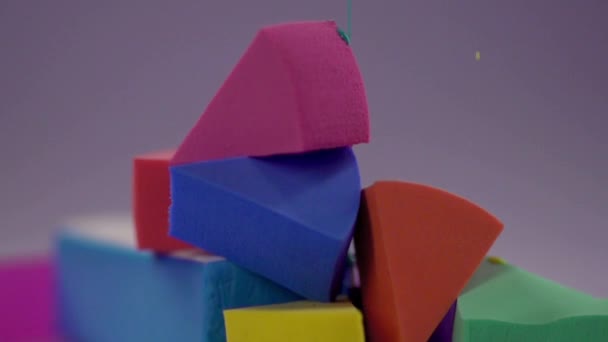 Eine bunte Farbe tropft zum Schminken vom Schwamm auf die Pyramide. — Stockvideo