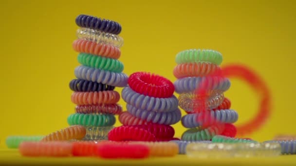 Torres de bandas de cabelo elásticas em espiral em um fundo amarelo — Vídeo de Stock