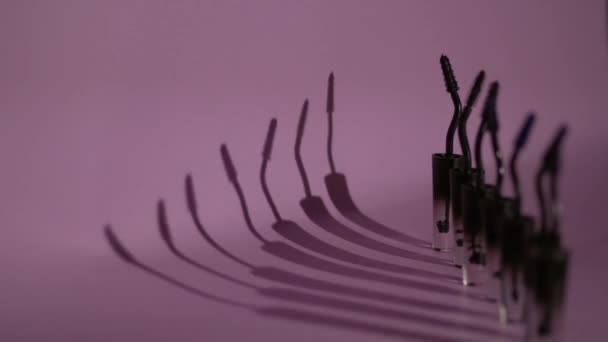 Brushes for mascara stand in a row on a purple background. — Stock Video