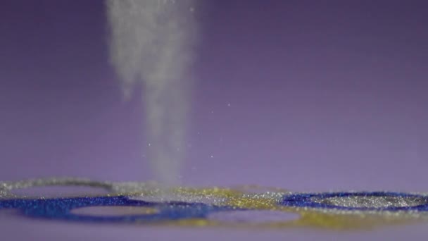 Il glitter multicolore viene depositato sulla superficie e sullo sfondo blu e bianco . — Video Stock