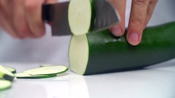 The fingers hold the cucumber and the knife quickly cuts into round slices. — Stock Video