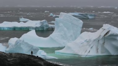 Antarktika arka planda bir dağ üzerinde bir adam duruyor. Andreev.