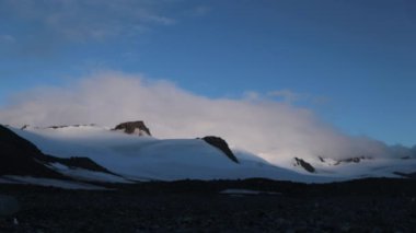 Karla kaplı dağlara gölge ve küçük çakıl taşları ile vadi manzarası. Andreev.