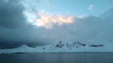 Dağları kar ile koyu gri bulutlar arka planı ile kaplıdır. Andreev.