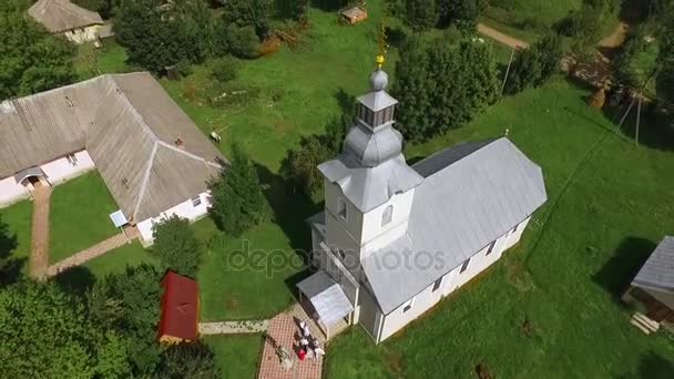 Photographie aérienne d'une petite église parmi les maisons de village et les forêts . — Video