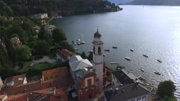 En gammal kyrka med ett klocktorn på stranden av sjön. — Stockvideo