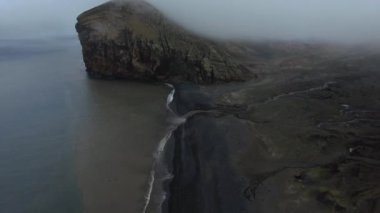 Cliff ve siyah sahilde kalıyor dalgalar ile bir görünüm. Andreev.