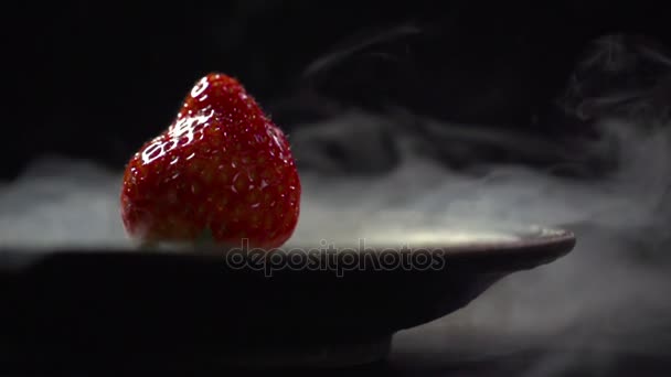 Aardbeien liggen in een bord met vloeibare stikstof. — Stockvideo