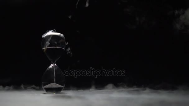 Black sand falls in the hourglass. — Stock Video