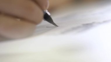 El calligraphically mürekkep ile kağıt üzerinde mektuplar yazıyor.