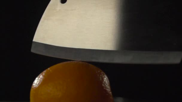 El hacha corta la naranja por la mitad . — Vídeo de stock