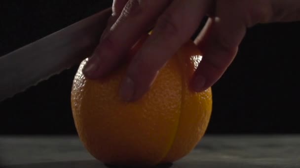 Het mes snijdt de helften van de oranje. — Stockvideo