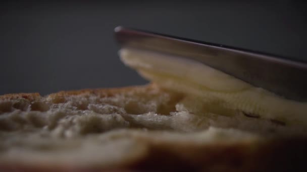 De boter is besmeurd met een mes op het brood. — Stockvideo