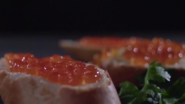 A branch of parsley slowly falls on a sandwich with red caviar — Stock Video