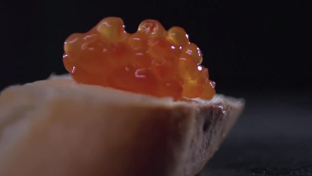 Una vista del caviar rojo asentamiento en un sándwich con mantequilla . — Vídeo de stock