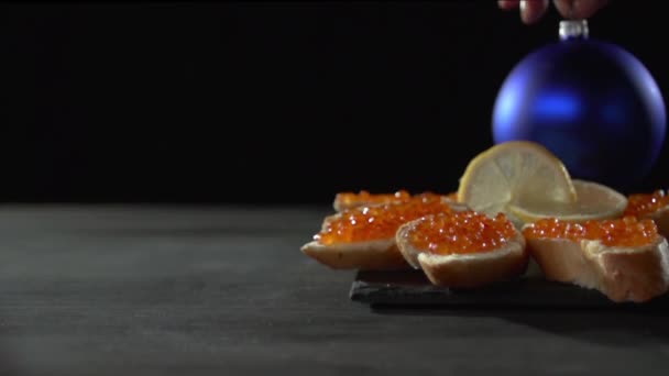 Eine blaue Weihnachtskugel wird vor Sandwiches in den Hintergrund gestellt. — Stockvideo