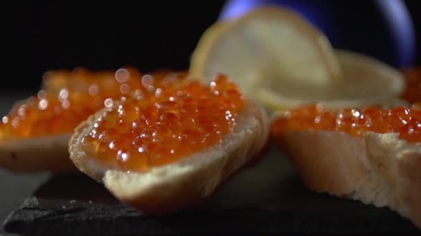 Close-up van een hand met een boterham met rode kaviaar. — Stockvideo