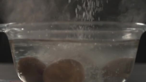 Un grand sel est versé dans un bocal en verre avec de l'eau chaude et des œufs .