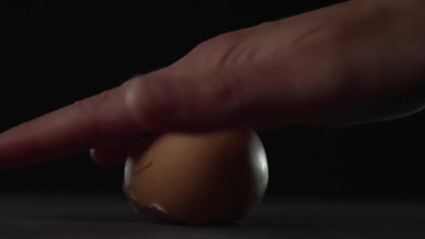 Рука раскатывает яйцо на поверхности и разбивает скорлупу. . — стоковое видео