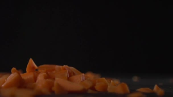 Sliced carrots fall on a pile of carrot. — Stock Video